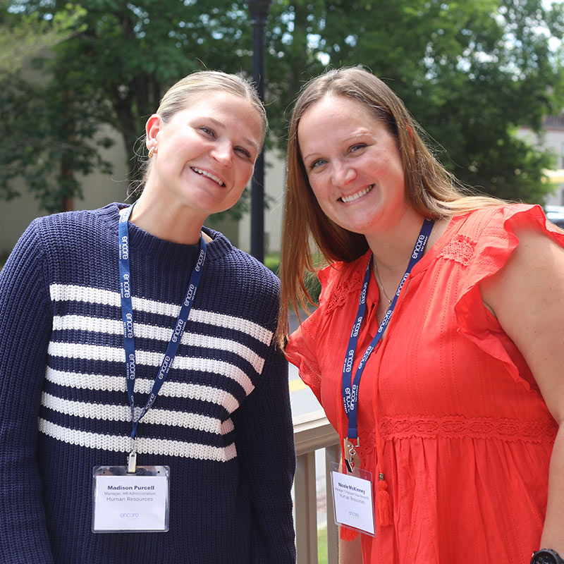 two members of Encore Vet Group posing and smiling outdoors