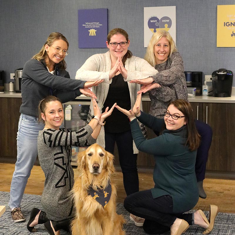 Group of Encore team members gathered together and posing with a golden retriever