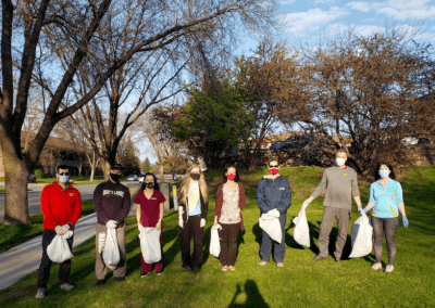 several people wearing face masks at the park and holding trash bags - ready to clean the park