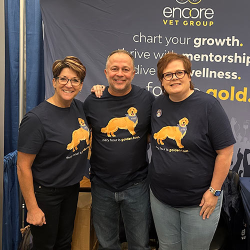 Encore team members standing together in front of an Encore banner and wearing dark blue Encore shirts