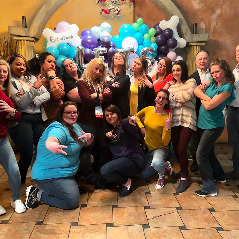 Group of Encore team members gathered together and posing with a golden retriever