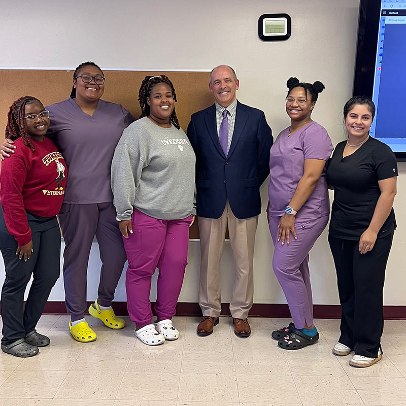 Dr. Tim Loonam standing with young women in the veterinary field